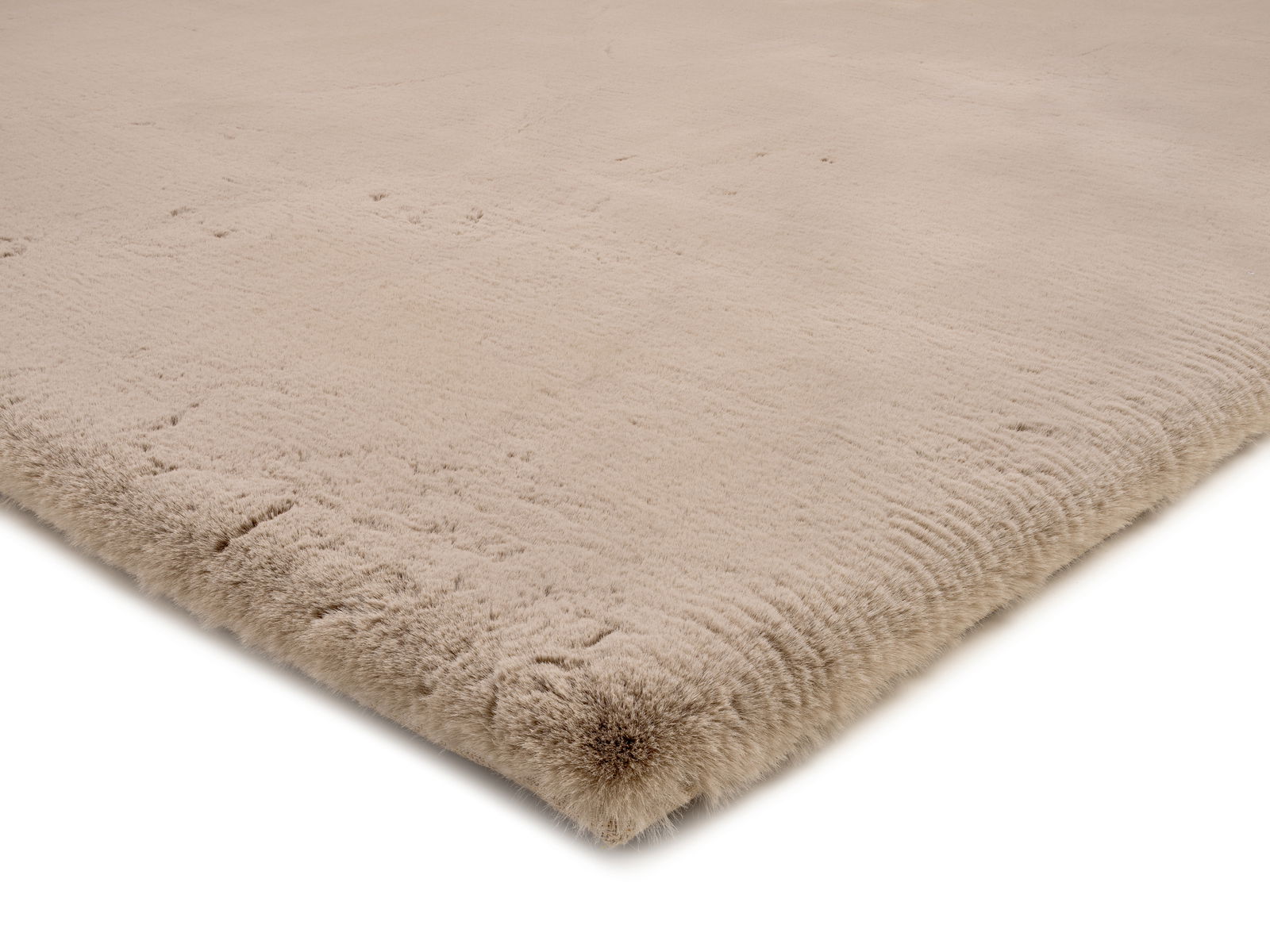 Nahaufnahme eines beigen Fellteppichs aus der Perspektive der Ecke, die die weiche Textur und die flauschige Oberfläche zeigt.