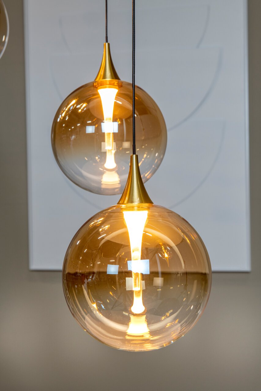 Moderne Hängeleuchte mit goldener Glaskugel und warmem Licht, seitliche Perspektive