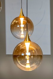 Moderne Hängeleuchte mit goldener Glaskugel und warmem Licht, seitliche Perspektive
