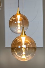 Moderne Hängeleuchte mit goldener Glaskugel und warmem Licht, seitliche Perspektive