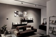 Modernes Wohnzimmer mit Schienenpendel Aldan, seitliche Perspektive, stilvolle Beleuchtung über einem Sofa und Regalen.