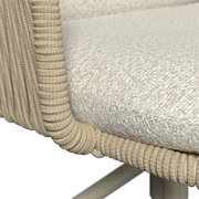 Detailaufnahme aus seitlicher Perspektive: gepolsterter Sitz mit hellbeigem, strukturiertem Stoffbezug und umlaufender, geflochtener Kordel-/Seilumrandung am Rahmen