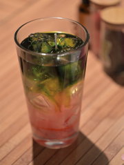 Creatieve kaars in een longdrinkglas met transparante groene en roze waslagen.