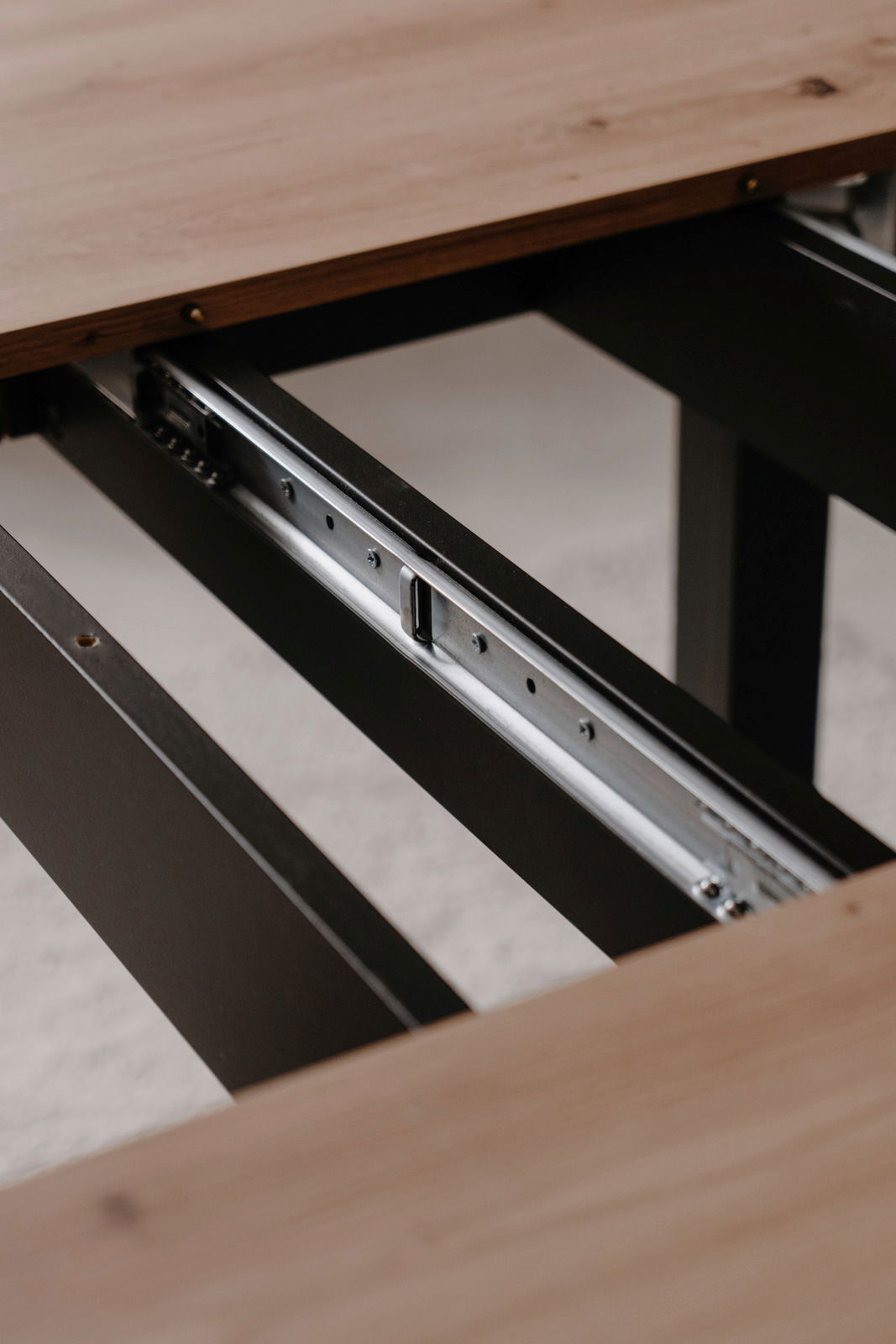 Nahaufnahme eines Esstisches mit ausziehbarer Metallführung, Perspektive von der Seite