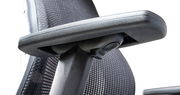 Nahaufnahme eines ergonomischen Drehstuhls mit Armlehne und Netzrückenlehne, seitliche Perspektive
