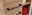 Nahaufnahme eines Midischranks aus Holz mit schwarzen Griffen, seitliche Perspektive, zeigt geöffnete Regale mit roten Handtüchern.