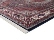 Orientteppich mit reichhaltigem, traditionellem Muster in Rot- und Blautönen, perspektivisch von der Ecke aus fotografiert.