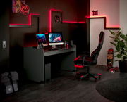 Moderner Schreibtisch in einem Gaming-Zimmer mit zwei Monitoren, Tastatur und Maus, umgeben von roten LED-Lichtern. Perspektive von der Seite.