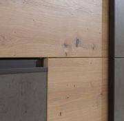 Nahaufnahme eines Schwebetürenschranks mit Holz- und Betonelementen, seitliche Perspektive.