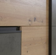 Nahaufnahme eines Schwebetürenschranks mit Holz- und Betonelementen, seitliche Perspektive.