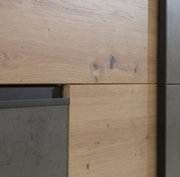 Nahaufnahme eines Schwebetürenschranks mit Holz- und Betonelementen, seitliche Perspektive.