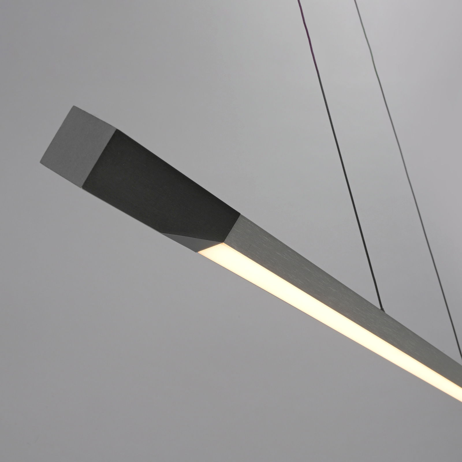 Moderne LED-Pendelleuchte in seitlicher Perspektive, schlankes Design mit mattem Finish und warmem Licht.