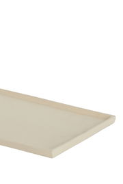 Nahaufnahme einer rechteckigen, flachen, cremefarbenen Schale aus seitlicher Perspektive.