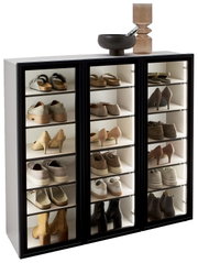 Schuhschrank-Vitrine mit drei Glastüren, gefüllt mit verschiedenen Schuhen, aus seitlicher Perspektive fotografiert.