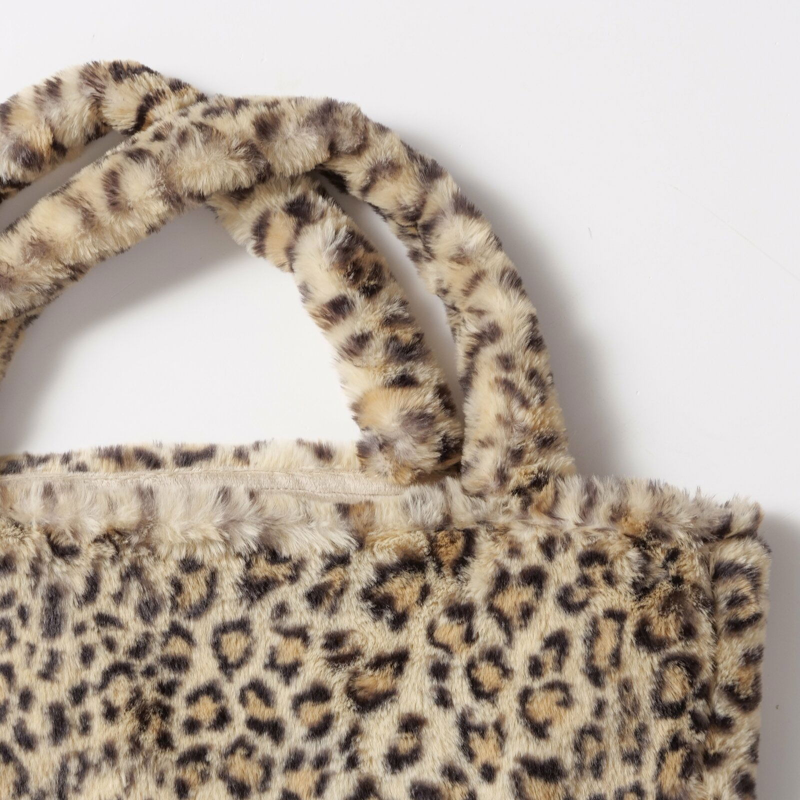 Nahaufnahme einer Tasche Leony mit Leopardenmuster und weichem, plüschigem Material, von oben betrachtet.