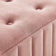 Close-up van een roze gestoffeerde zitbank met knoopdetails en verticale naden, gefotografeerd vanuit een perspectief van bovenaf.