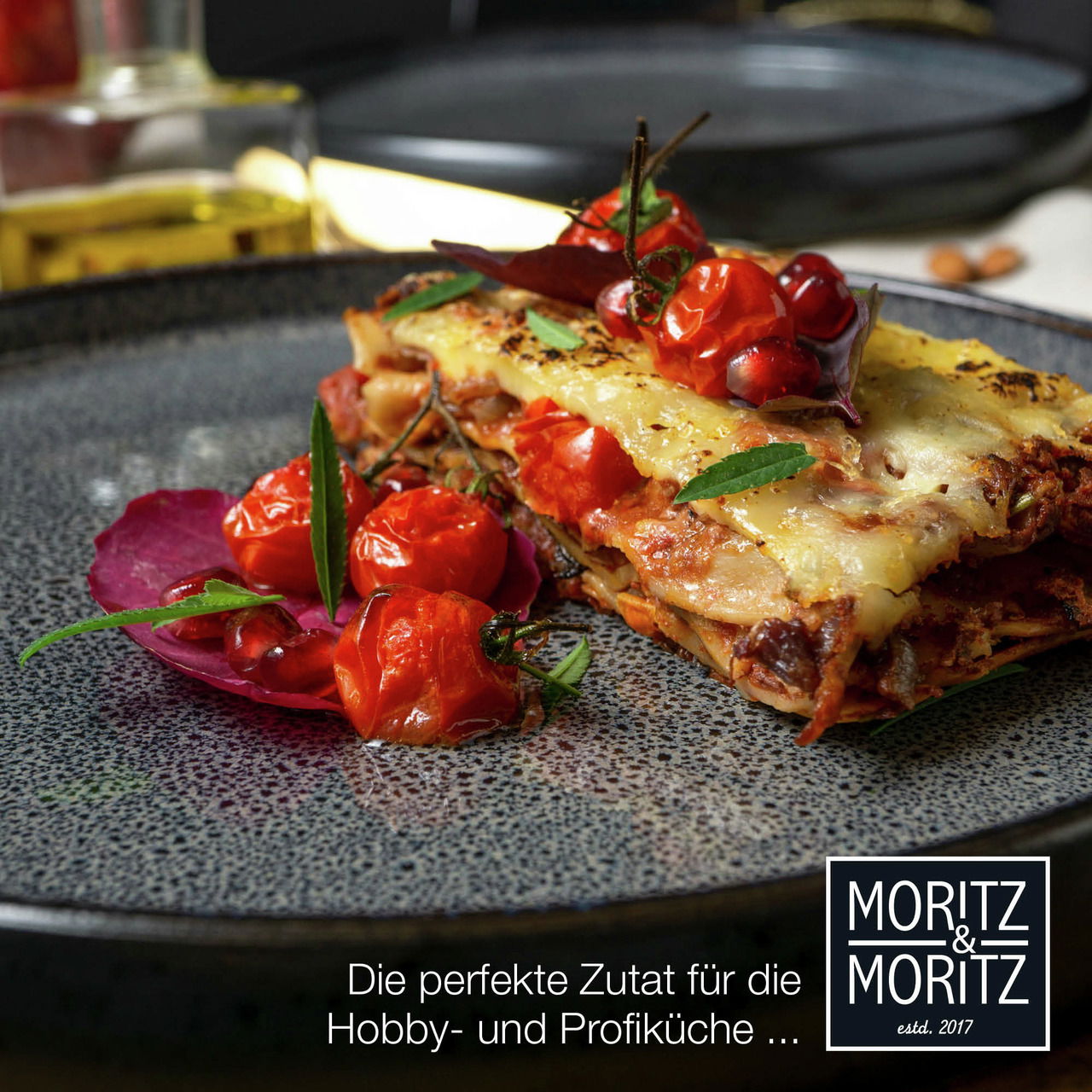 Nahaufnahme eines eleganten grauen Tellers mit einer Portion Lasagne, garniert mit frischen Tomaten und Kräutern, ideal für Hobby- und Profiköche.