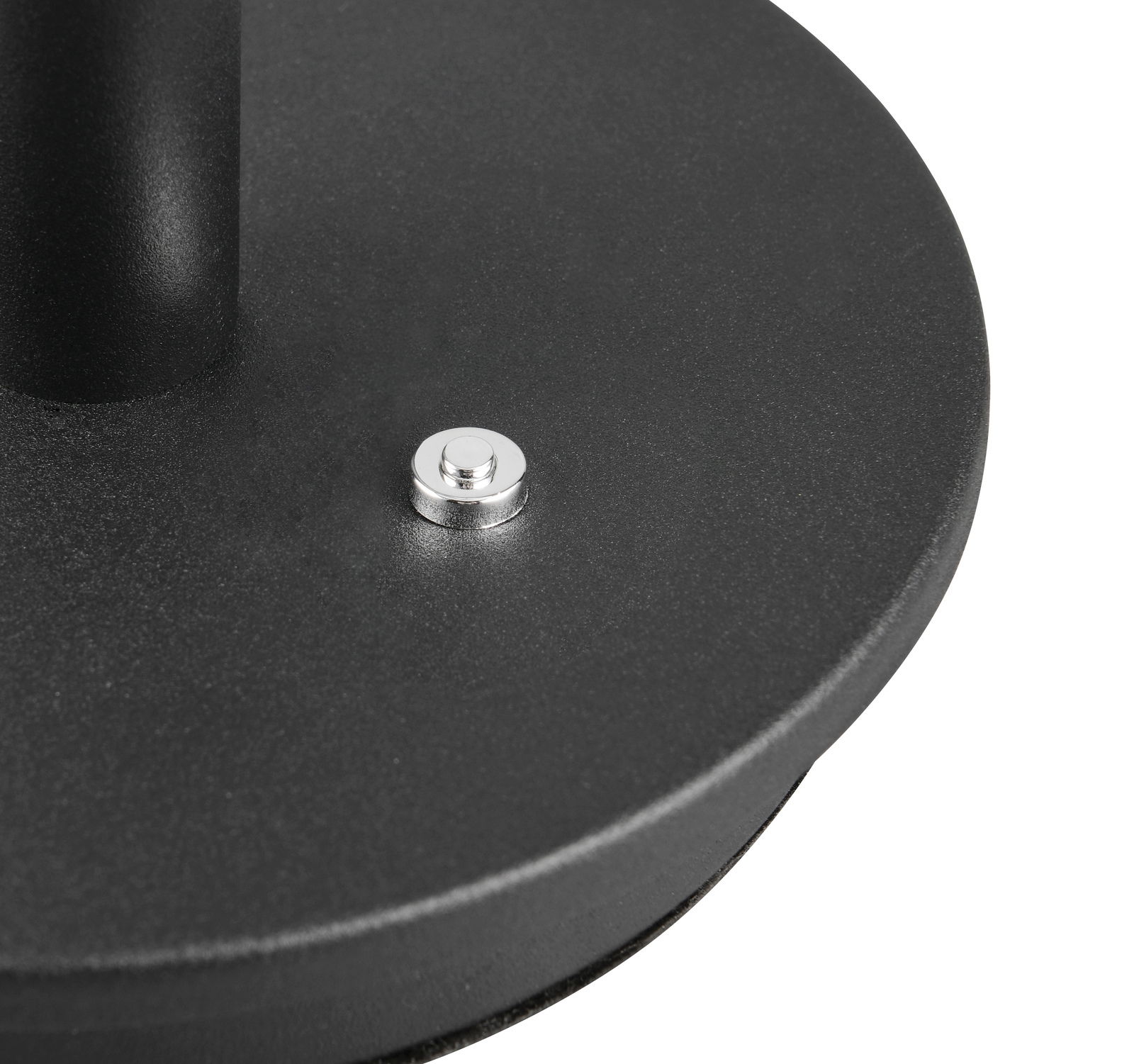 Nahaufnahme der Basis einer schwarzen Tischleuchte mit silbernem Schalter, von oben betrachtet.