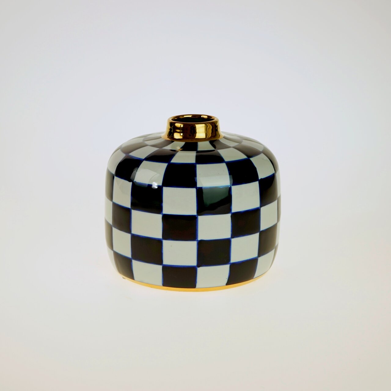 Handbemalte Vase Harlekin mit schwarz-weißem Karomuster und goldener Öffnung, frontal fotografiert.