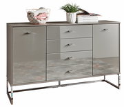 Moderne Kombikommode mit glänzender Oberfläche, zwei Türen und vier Schubladen, frontal abgebildet. Dekoriert mit einem Drahtkorb, Pflanzen und Büchern.