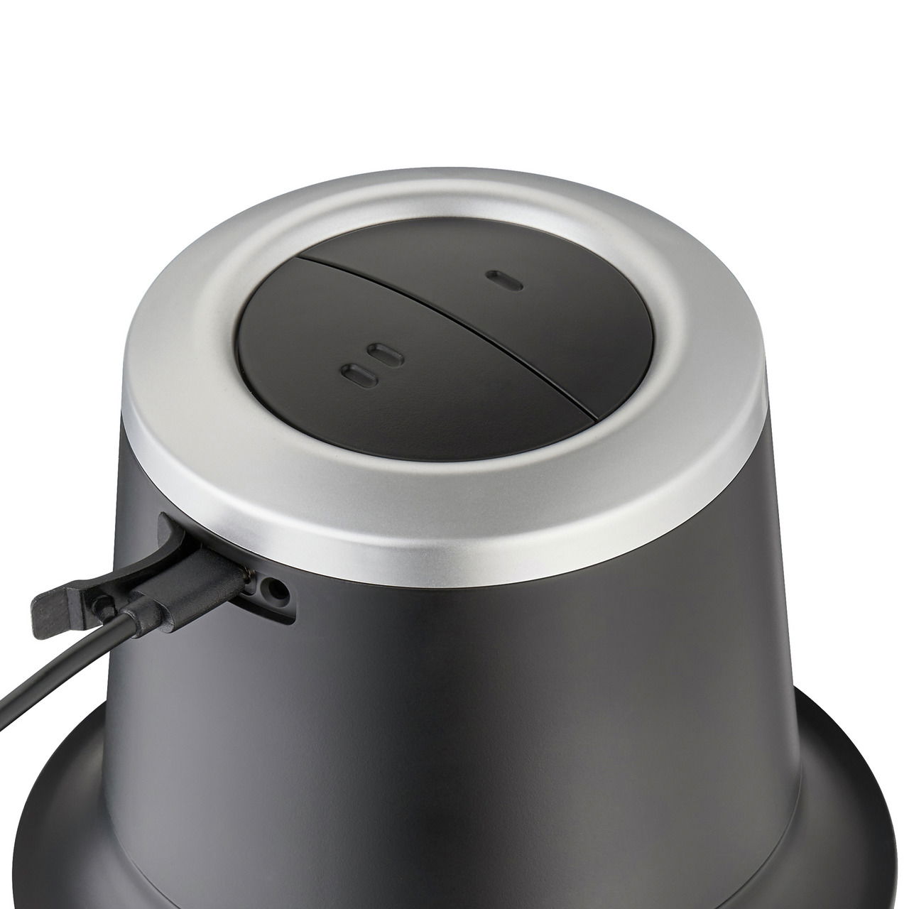 Nahaufnahme eines schwarzen Akku-Multizerkleinerers mit silbernem Rand und Kabelanschluss, von oben betrachtet.