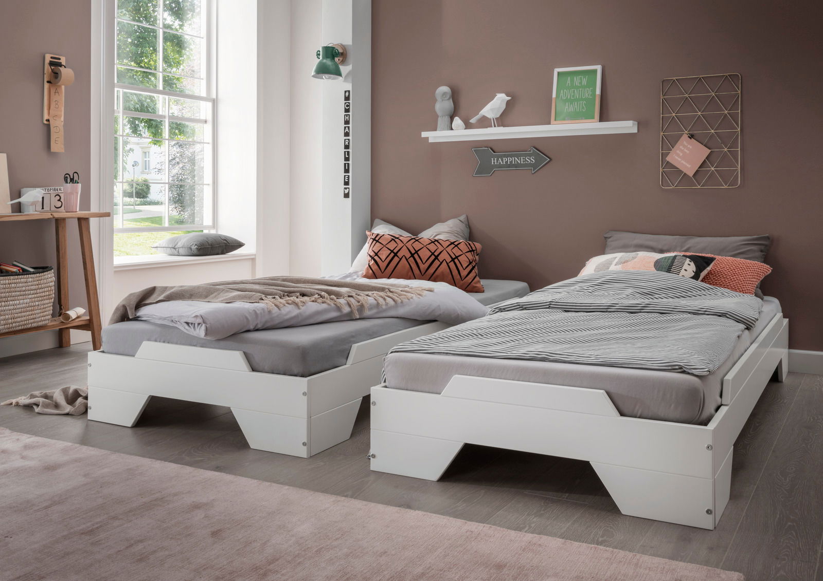Zwei weiße Stapelbetten in einem modernen Schlafzimmer mit großen Fenstern, seitliche Perspektive