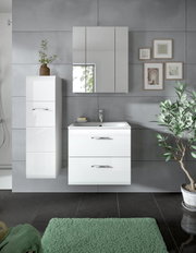 Modernes Badezimmer-Set mit weißem Waschtischunterschrank mit zwei Schubladen, Waschbecken und Armatur, passendem Spiegelschrank sowie hohem Hängeschrank vor grauer Fliesenwand, frontal aus leicht erhöhter Perspektive.