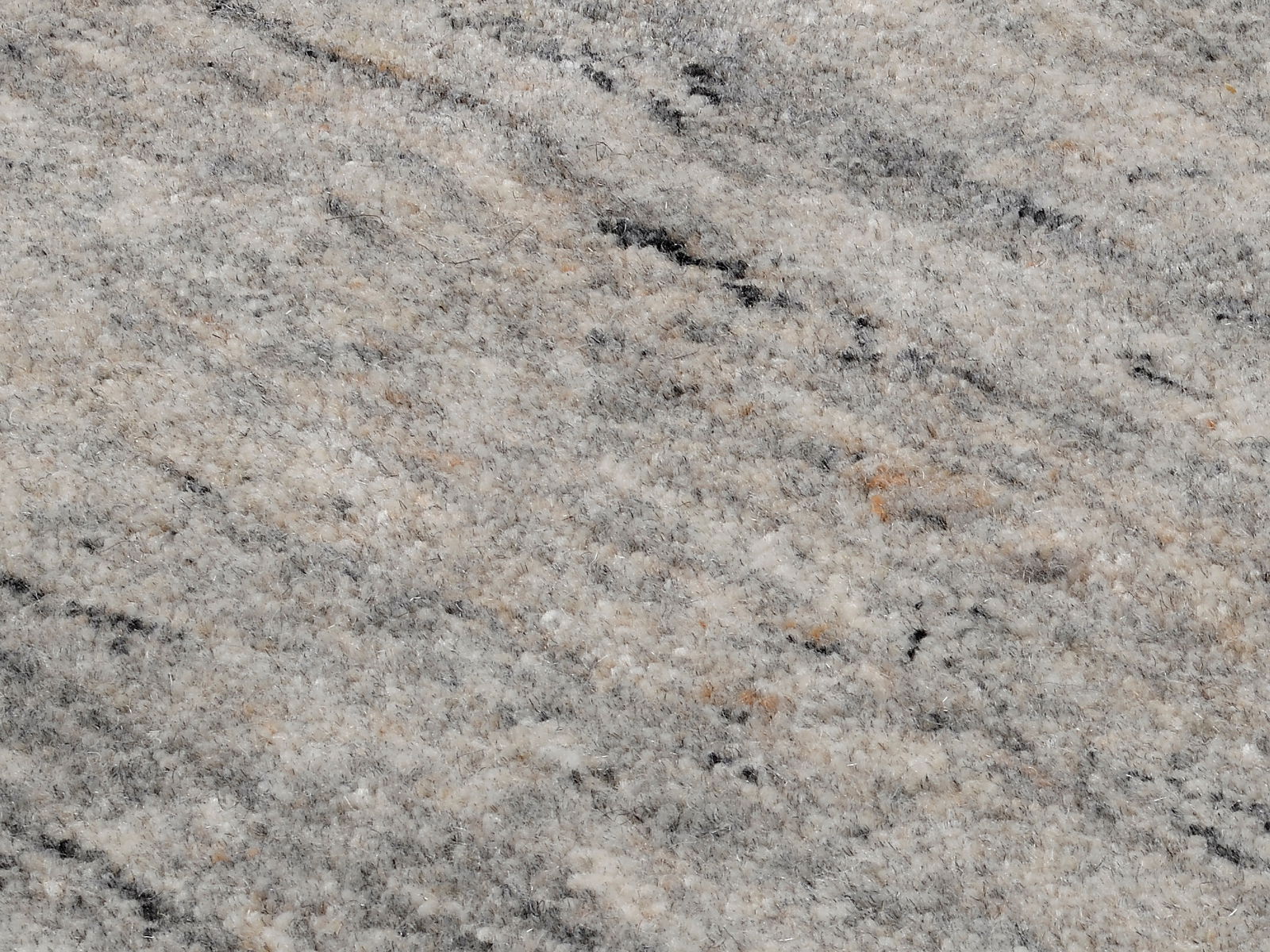 Nahaufnahme eines Wollteppichs mit grauen und beigen Farbtönen, von oben betrachtet.