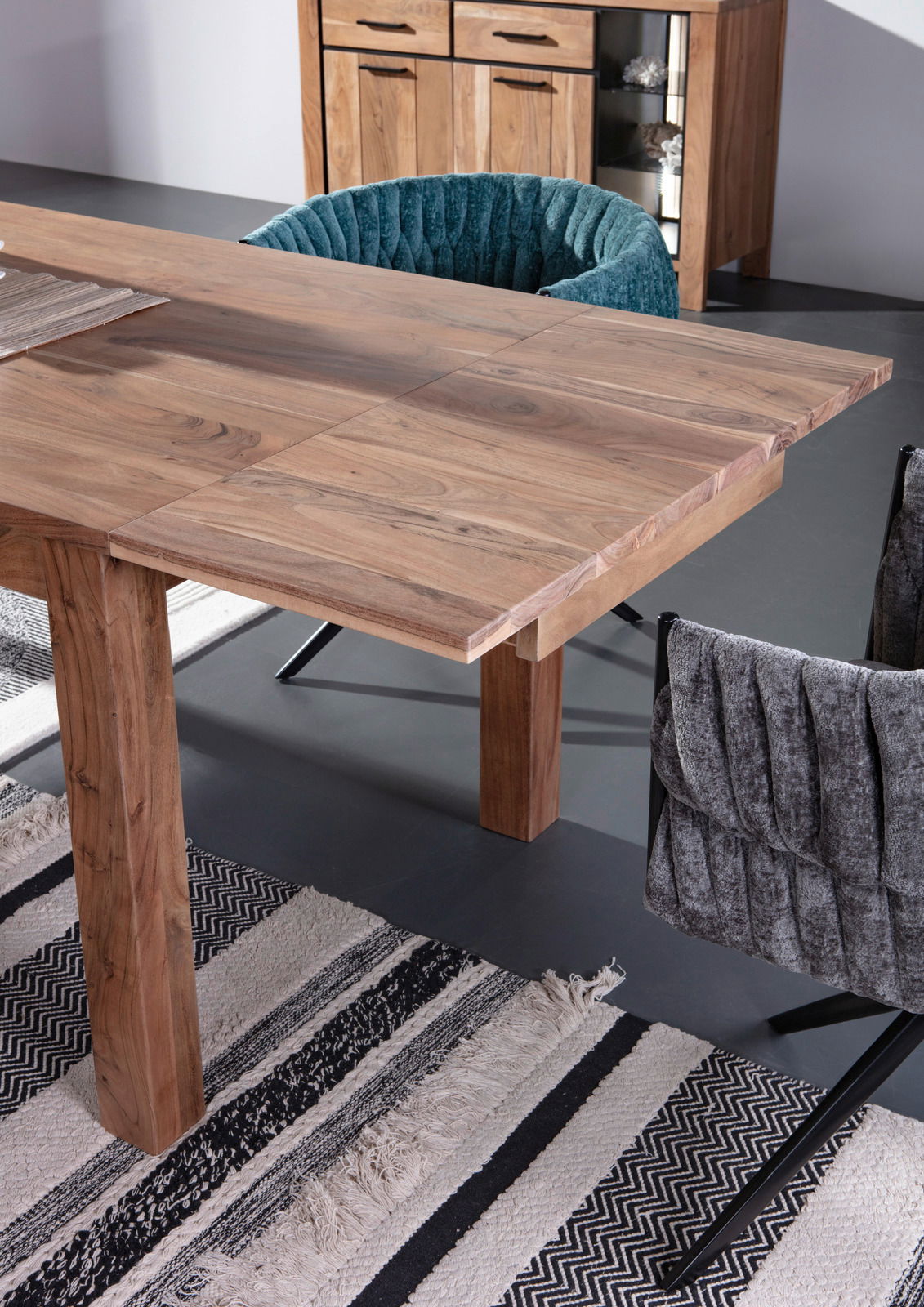 Esstisch aus Holz mit erweiterbarer Tischplatte, umgeben von gepolsterten Stühlen, aus der Vogelperspektive fotografiert.