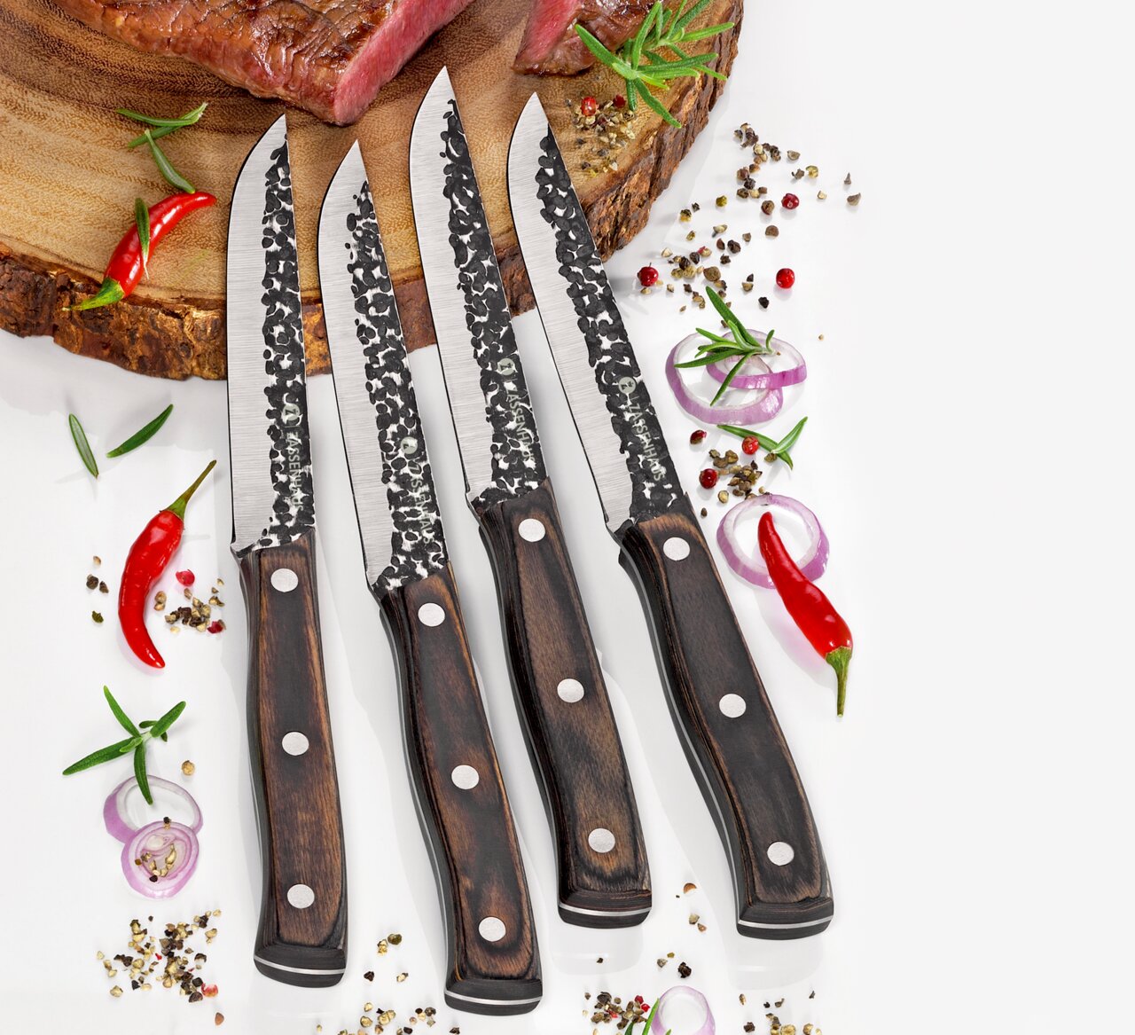 Vier Steakmesser HUNTER mit gehämmerten Klingen und Holzgriffen, von oben fotografiert, auf einem Schneidebrett mit Gewürzen und Chili.