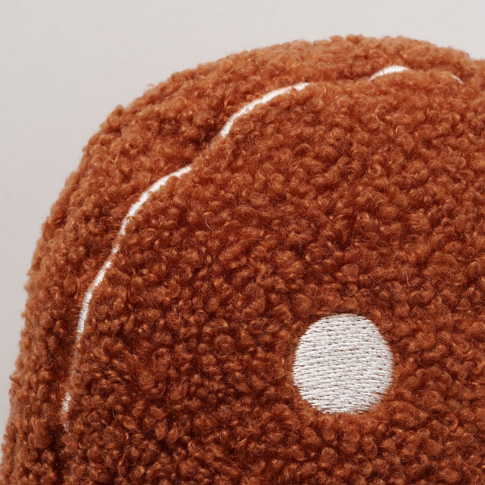Nahaufnahme eines braunen, flauschigen Kissens mit weißem Punktmuster, Perspektive von oben.