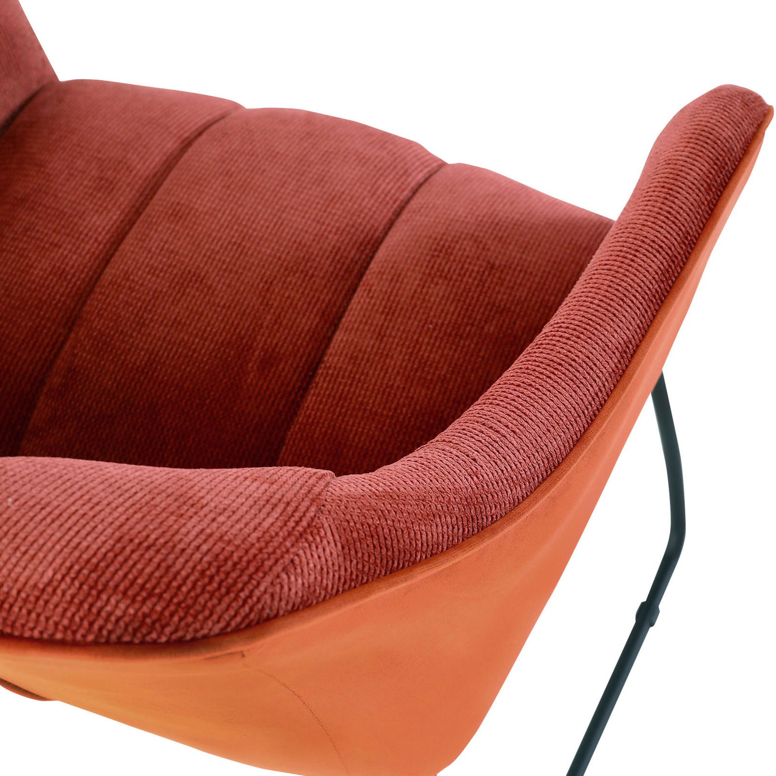 Nahaufnahme eines roten Armlehnstuhls mit weicher Polsterung und schwarzem Metallgestell, seitliche Perspektive