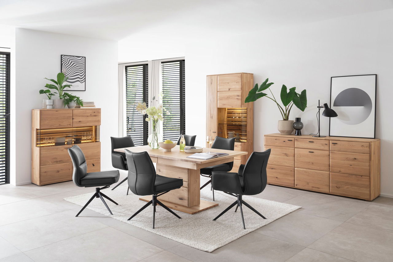 Esszimmer mit modernem Highboard aus Holz, umgeben von schwarzen Stühlen und einem Holztisch, seitliche Perspektive