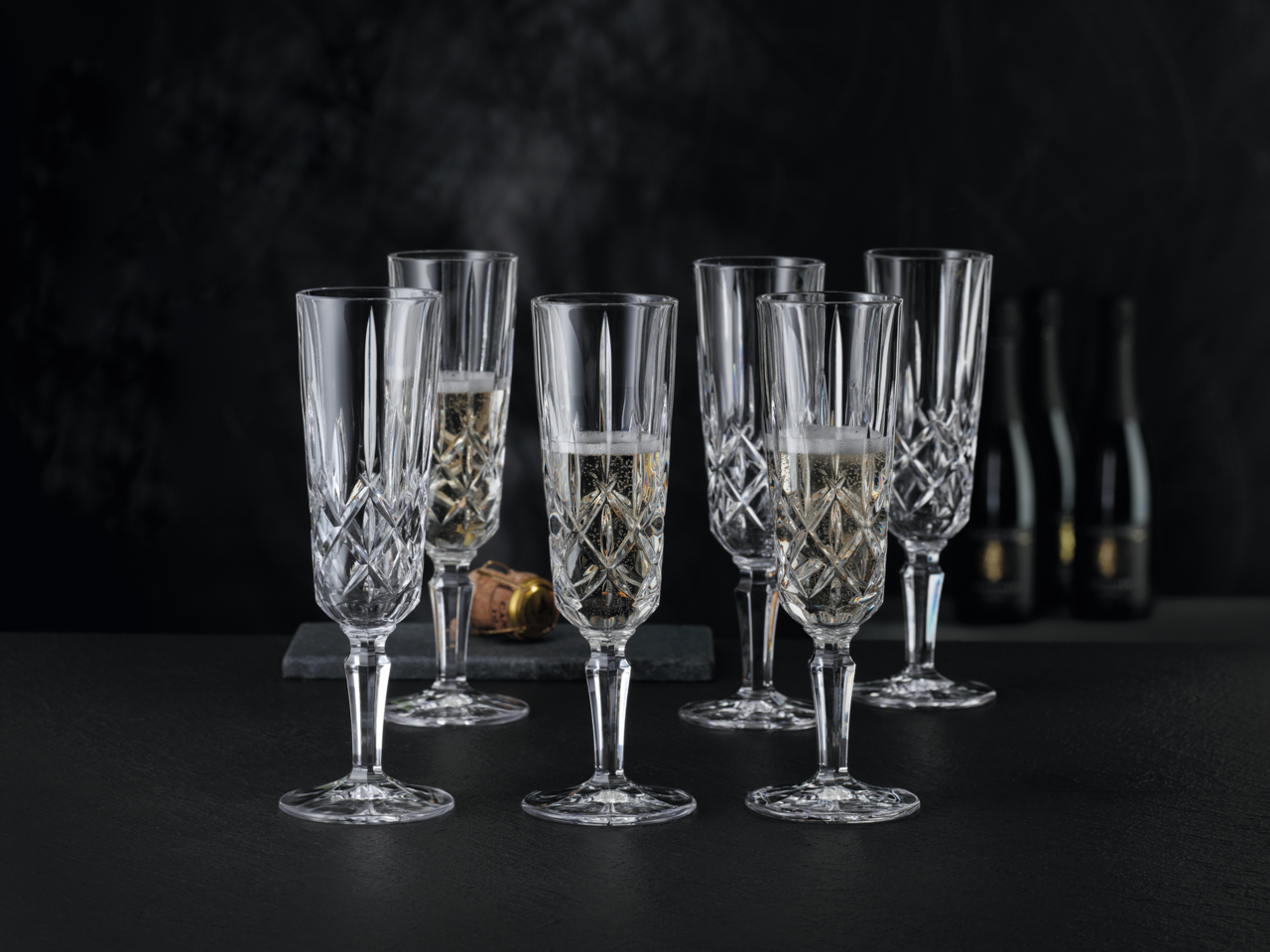 Nachtmann Champagnerglas 6er Set NOBLESSE Sechs elegante Champagnergläser aus Kristallglas mit feinem Schliff, gefüllt mit Champagner, auf schwarzem Hintergrund. Perspektive von vorne.
