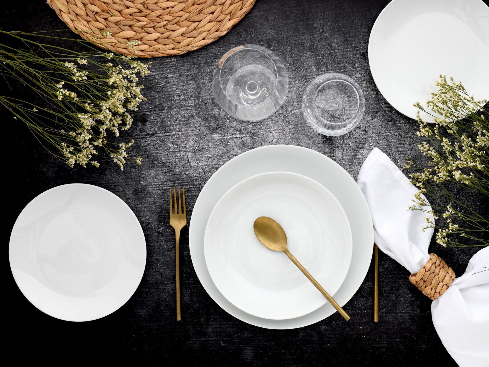 creaTable Tellerset 18-tlg LUNA Elegantes Tellerset 18-tlg in Vogelperspektive, mit goldfarbenem Besteck und dekorativen Blumen auf dunklem Hintergrund.