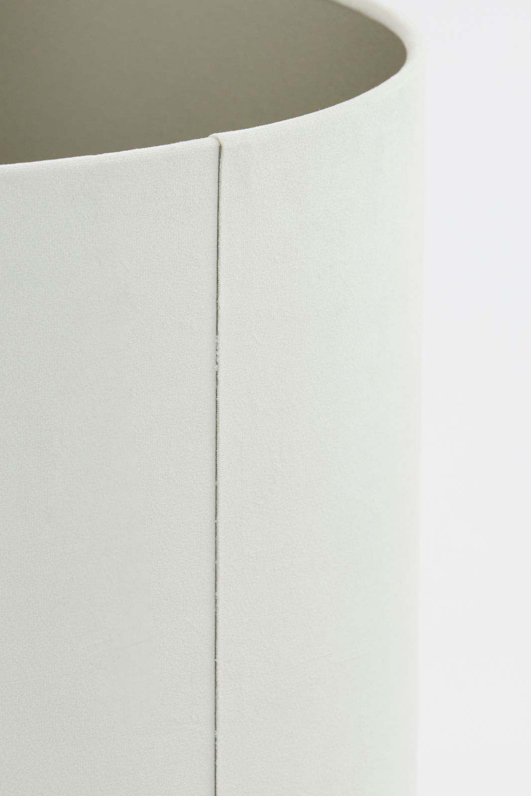 Nahaufnahme eines zylindrischen, hellen Lampenschirms aus Stoff, seitliche Perspektive