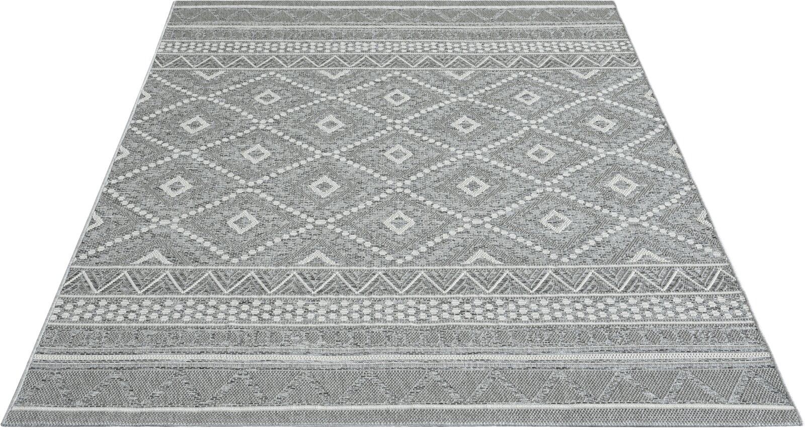 Grauer Teppichläufer mit geometrischem Rauten- und Bordürenmuster, in schräger Perspektive von oben fotografiert