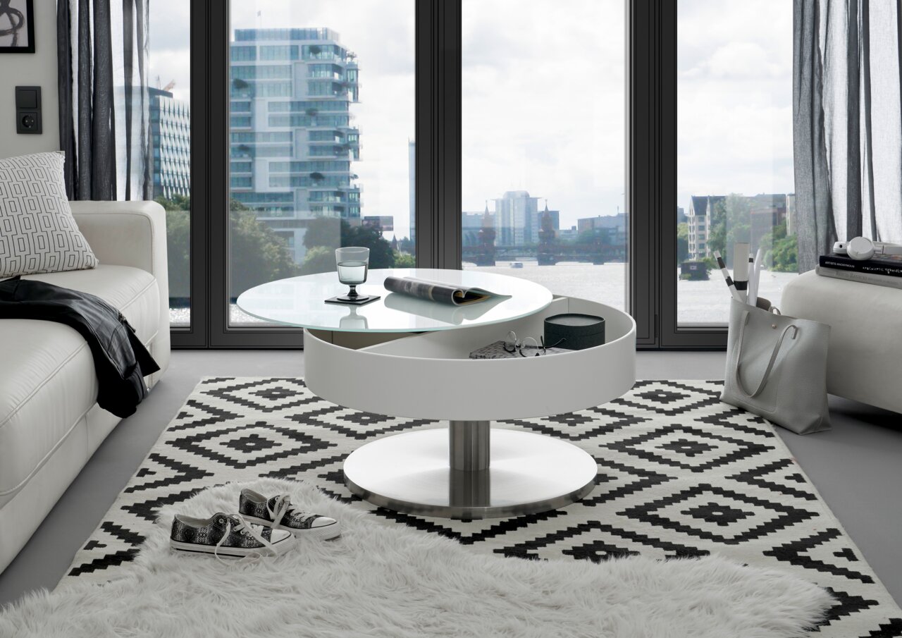 Moderner Couchtisch mit rundem, drehbarem Glasaufsatz und Stauraum, in einem stilvollen Wohnzimmer mit Blick auf die Stadt.