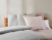 Bett mit Wendebettwäsche in sanften Pastelltönen, frontal aufgenommen
