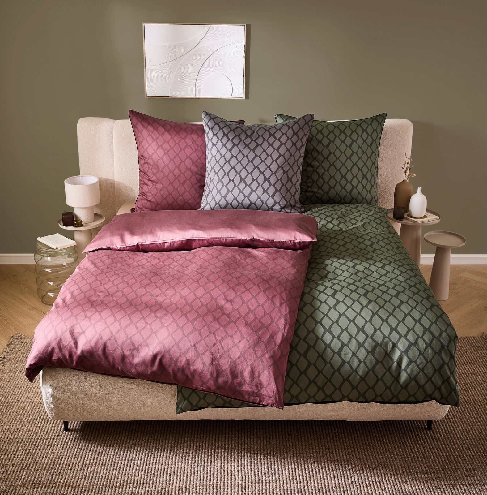 Wendebettwäsche in einem modernen Schlafzimmer, mit einer Seite in Rosa und der anderen in Grün, aus der Perspektive von vorne fotografiert.