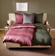 Wendebettwäsche in einem modernen Schlafzimmer, mit einer Seite in Rosa und der anderen in Grün, aus der Perspektive von vorne fotografiert.