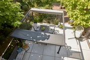 Blick von oben auf eine moderne Terrasse mit Pergola, Gartenmöbeln und üppiger Bepflanzung.