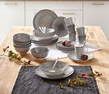 Kombiservice Tokyo 30-tlg. in einer modernen Küche, von oben fotografiert. Das Set besteht aus Tellern, Schalen und Tassen mit schwarzem geometrischem Muster.