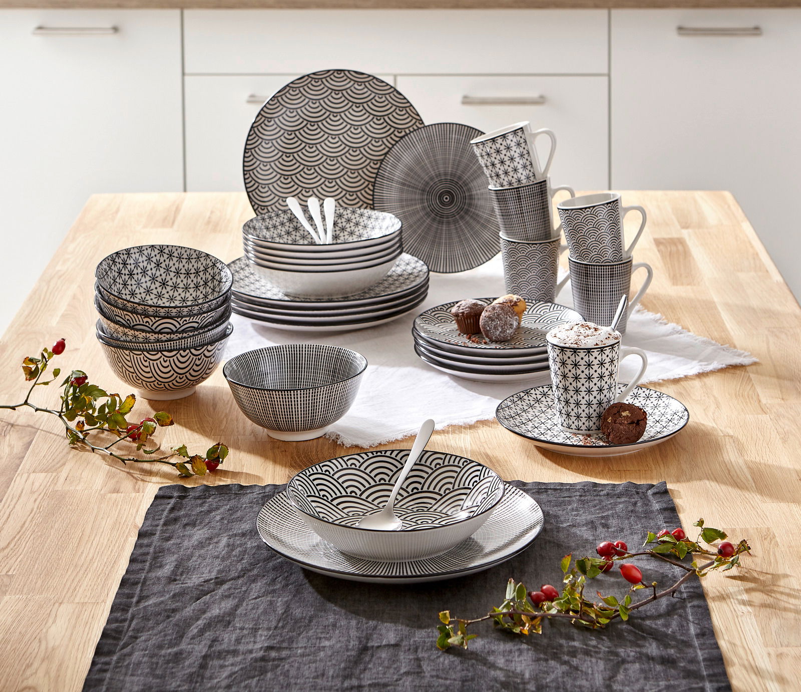 Kombiservice Tokyo 30-tlg. in einer modernen Küche, von oben fotografiert. Das Set besteht aus Tellern, Schalen und Tassen mit schwarzem geometrischem Muster.