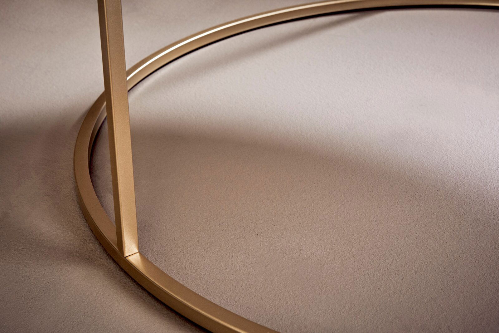 Nahaufnahme eines goldenen Couchtischgestells mit runder Basis, seitliche Perspektive.