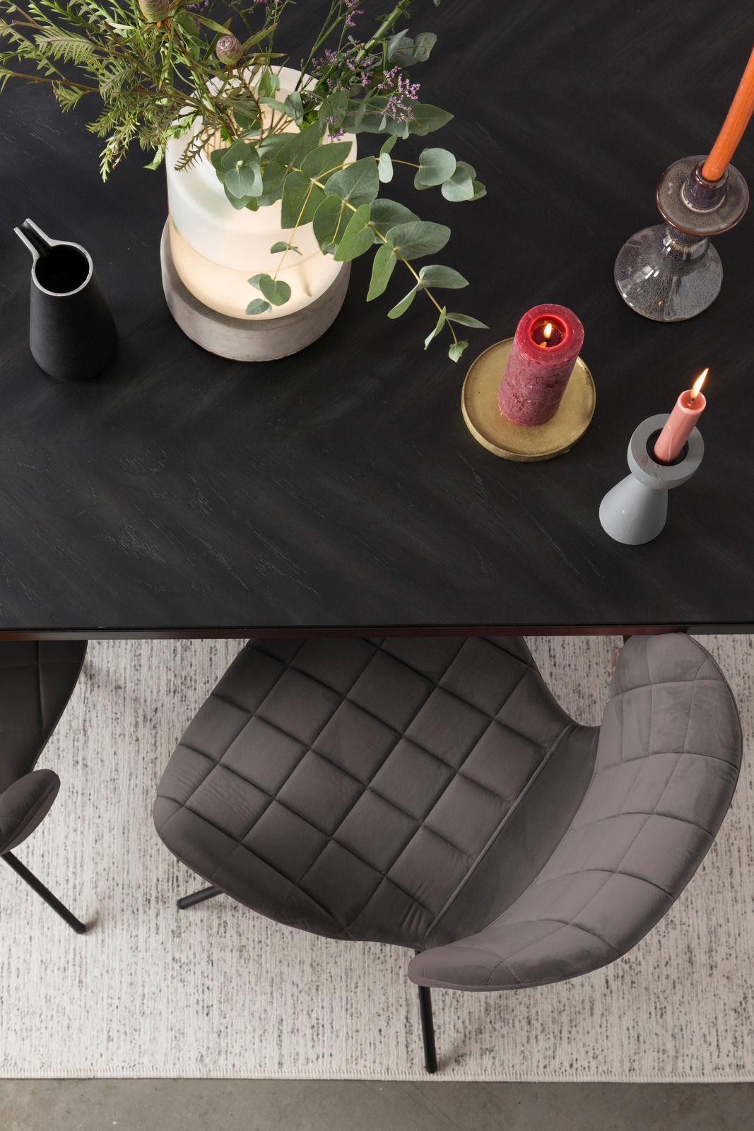 Z2 Stuhl OMG Draufsicht auf einen eleganten, gepolsterten Stuhl mit schwarzem Metallgestell, neben einem Tisch mit Kerzen und Pflanzen.