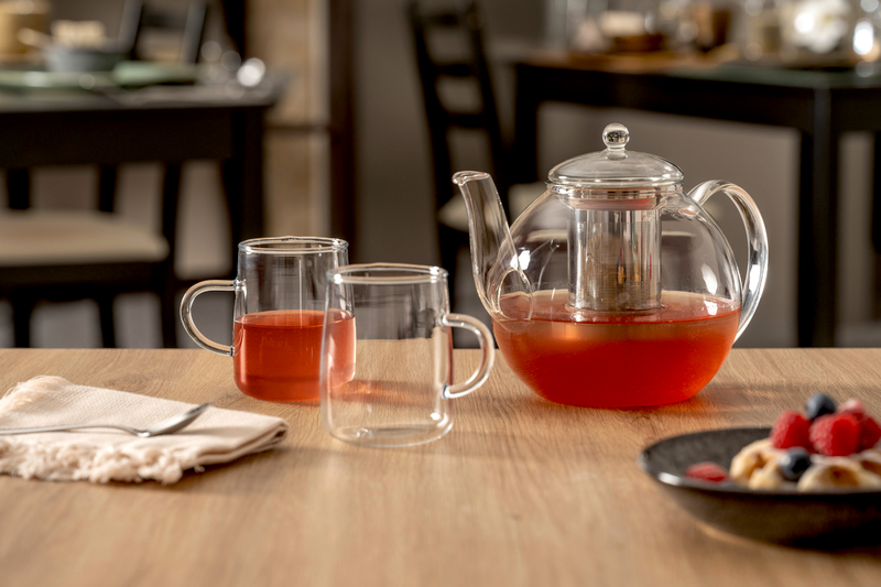 Leonardo Tee-Set 3-tlg. LIMITED EDITION Glas-Teekanne mit integriertem Sieb und zwei Glastassen, gefüllt mit rotem Tee, auf einem Holztisch. Perspektive: seitlich.