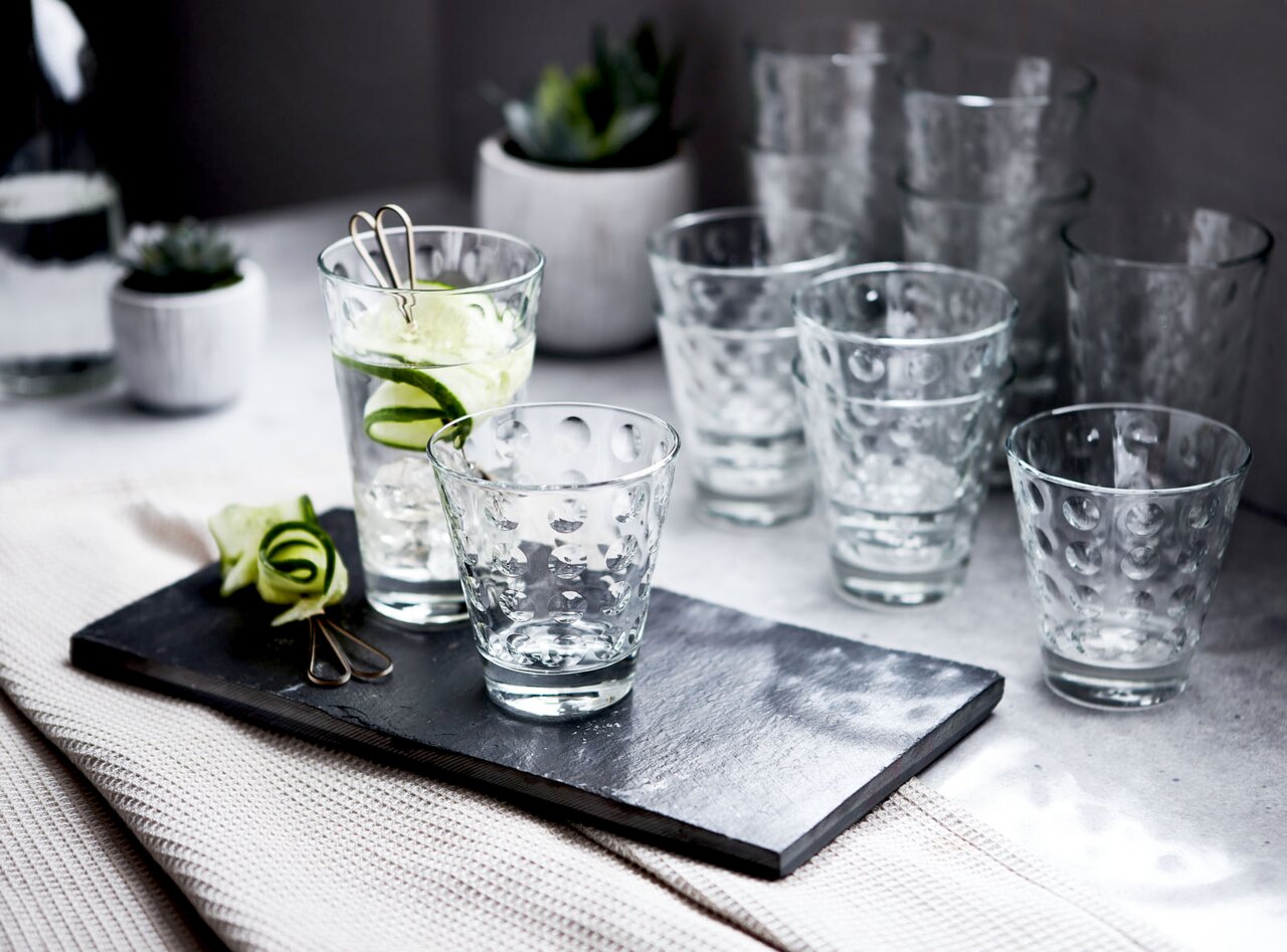 Ein Set von zwölf Gläsern mit optischem Design, präsentiert auf einem Tisch mit einer modernen und eleganten Perspektive.