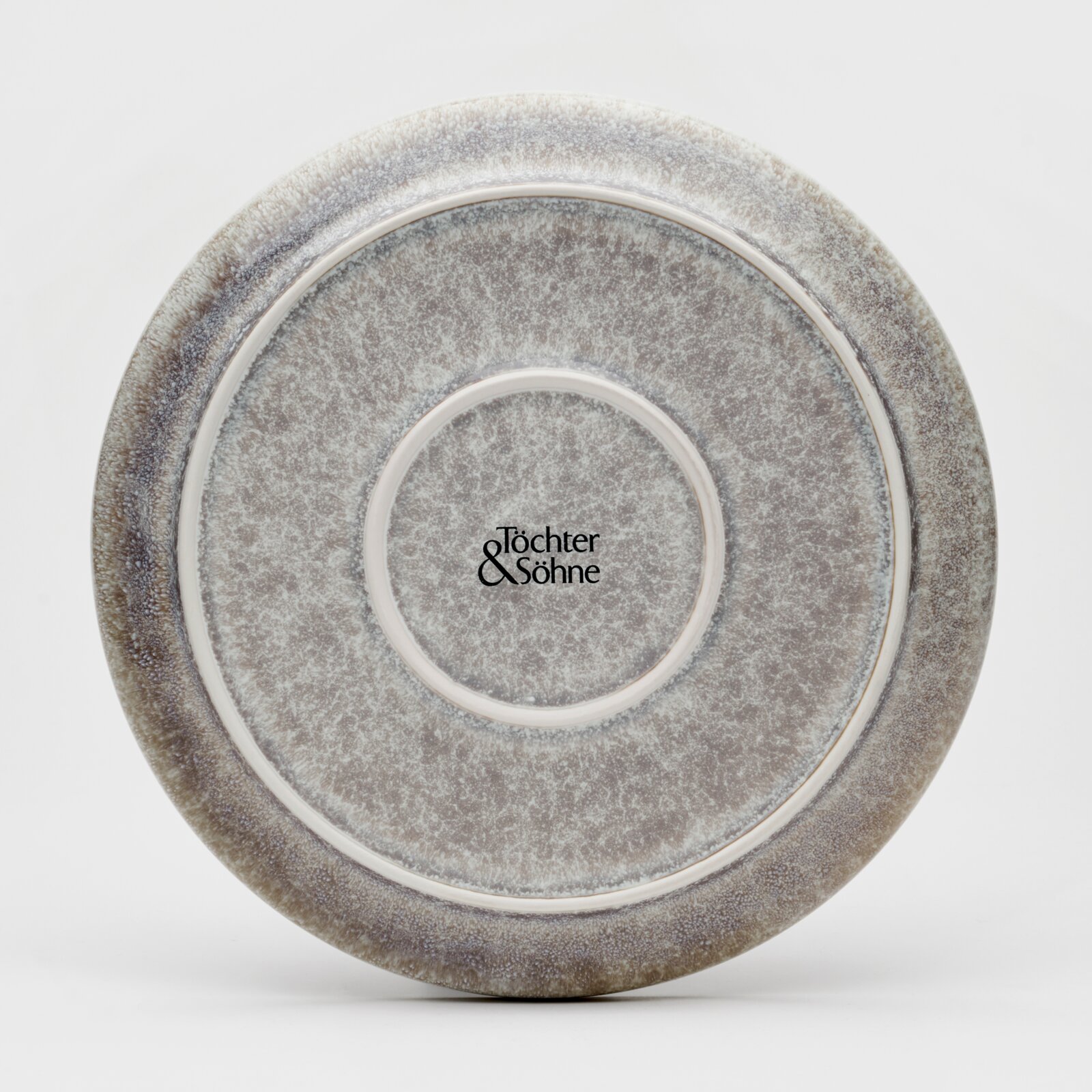 Achterkant van een bord met een grijs, gespikkeld patroon en het logo 'Töchter & Söhne' in het midden.