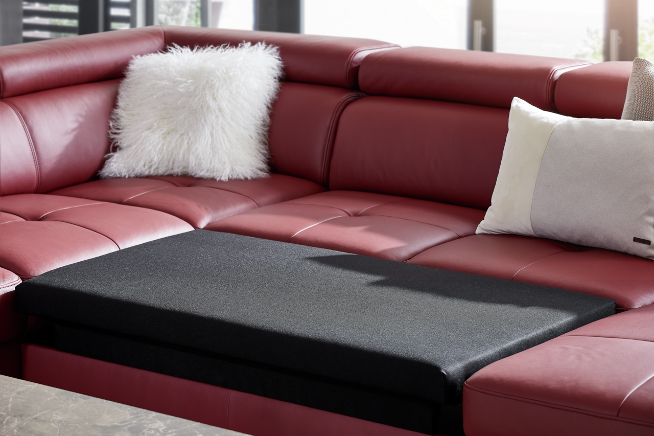 Rote Polsterrundecke TORINO mit Bettfunktion, Nahaufnahme von der Seite, mit weißen und grauen Kissen.